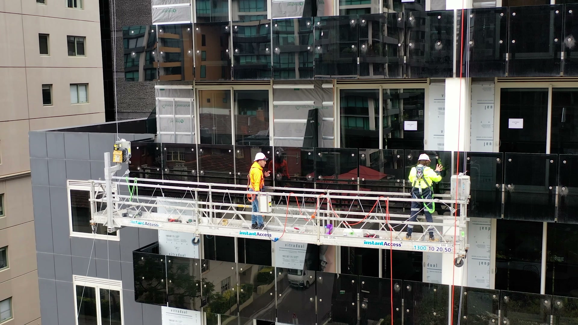 Pro-Build Plus crew on a suspended swing stage removing façade panels from a glass tower